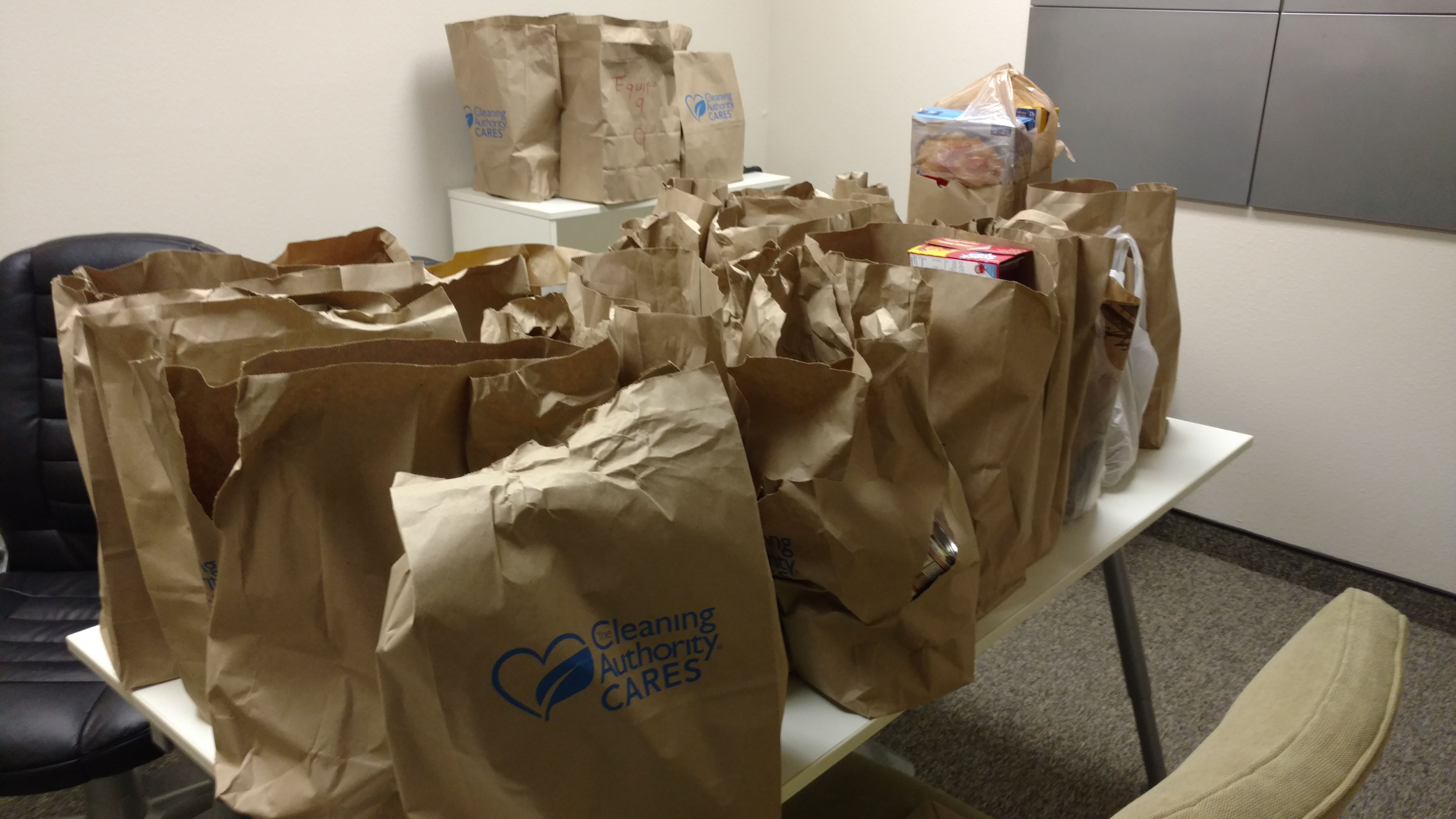 Paper bags full of donations collected by the TCA Irvine team are on a white table.
